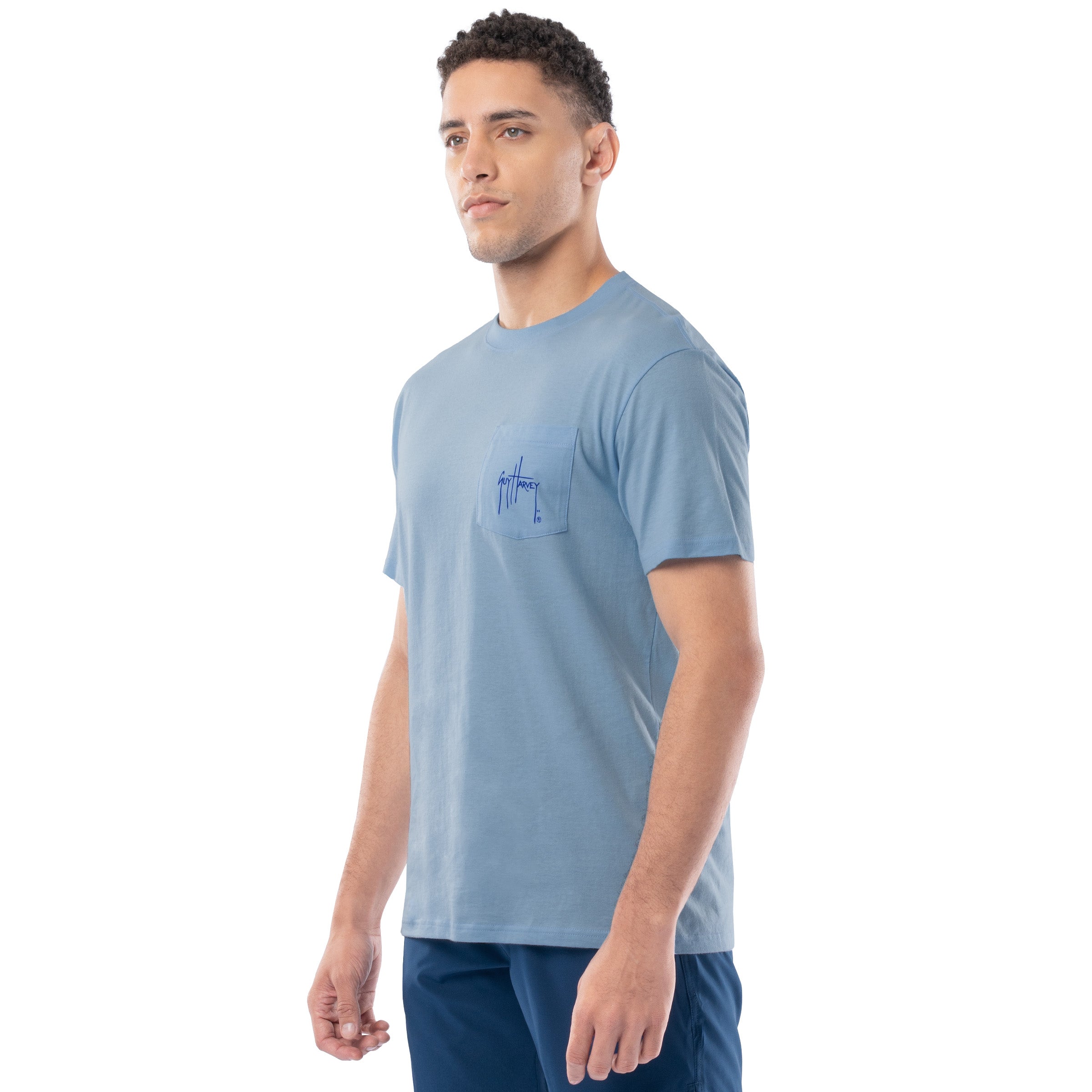 Man wearing a light blue t-shirt with a small logo on a white background