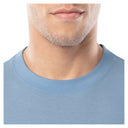 Close-up of a person wearing a light blue shirt with a plain background