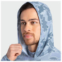 A man wearing a light blue and gray camouflage hooded shirt, shown from the chest up against a plain light gray background.