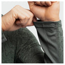 Close-up of a person's hands pulling up the cuff of a dark olive green long-sleeve marlin air sun protection hoodie, showing the breathable mesh fabric and curved seam.