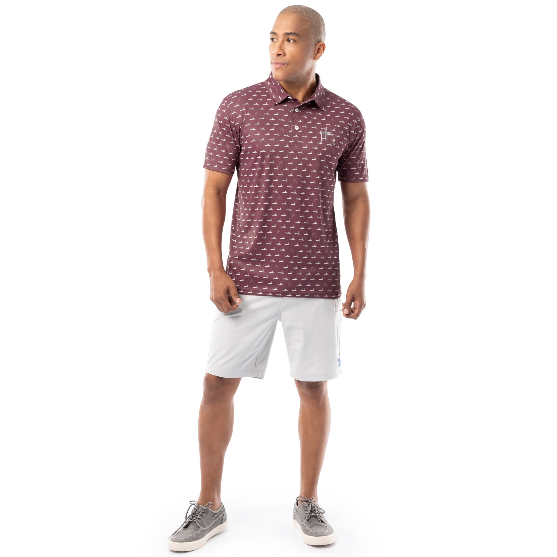 Lifestyle image of model wearing red wine Guy Harvey Men’s Red Fleet Printed Performance Polo with white shorts.