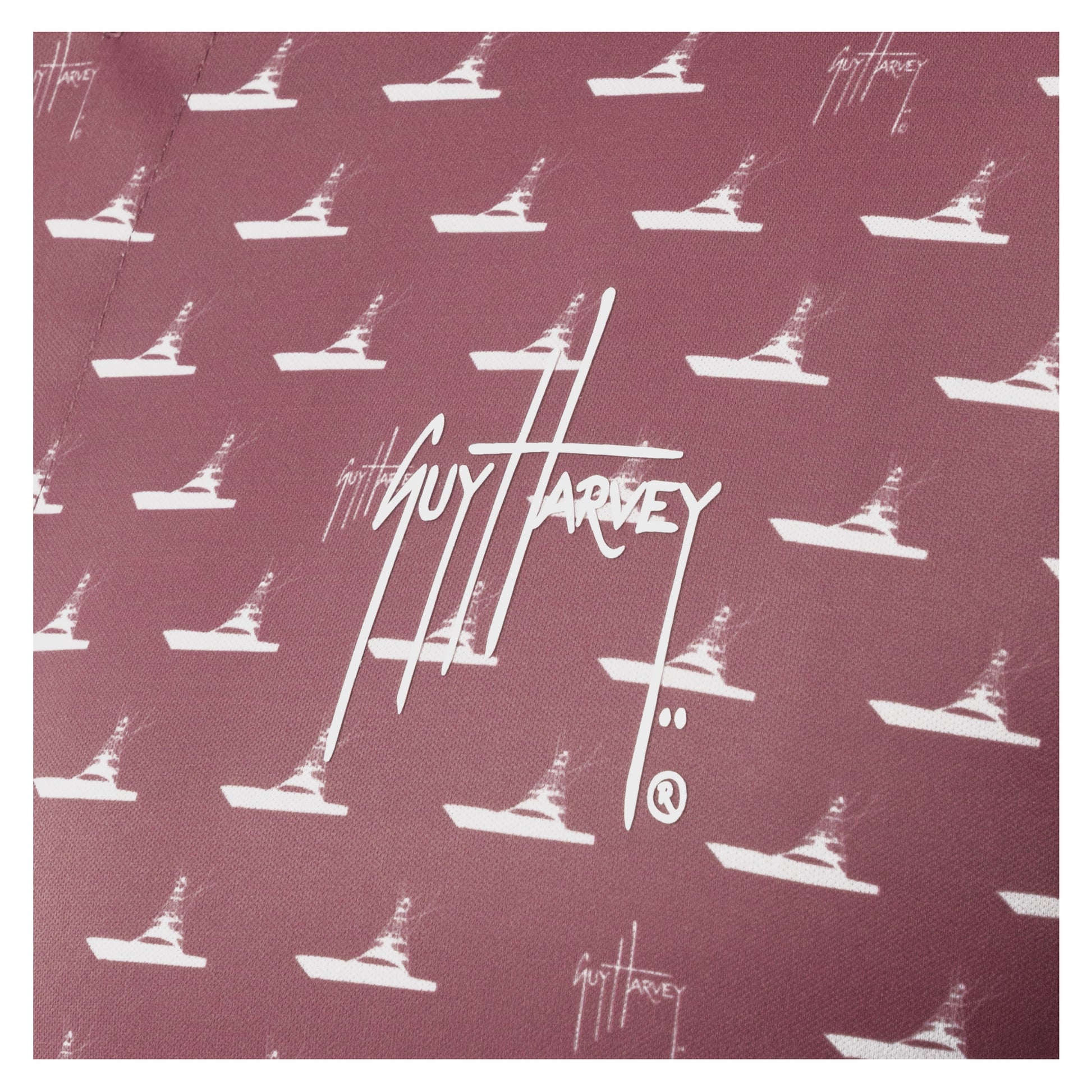 Detail of white Guy Harvey signature logo and boat print on red wine fabric.