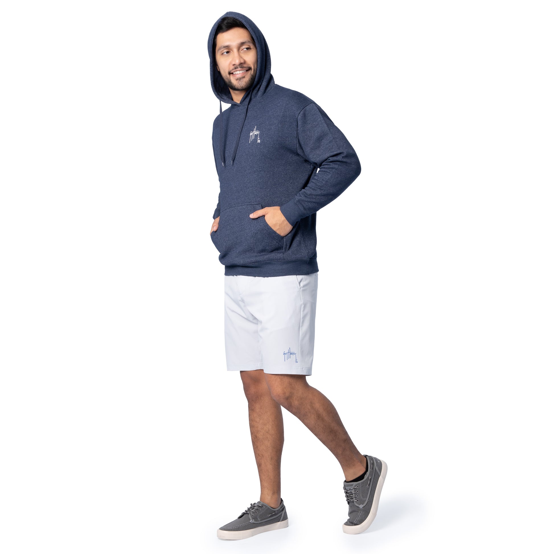 Full-body view of a man wearing a navy blue Guy Harvey fishing fleece hoodie with hood up and light shorts.