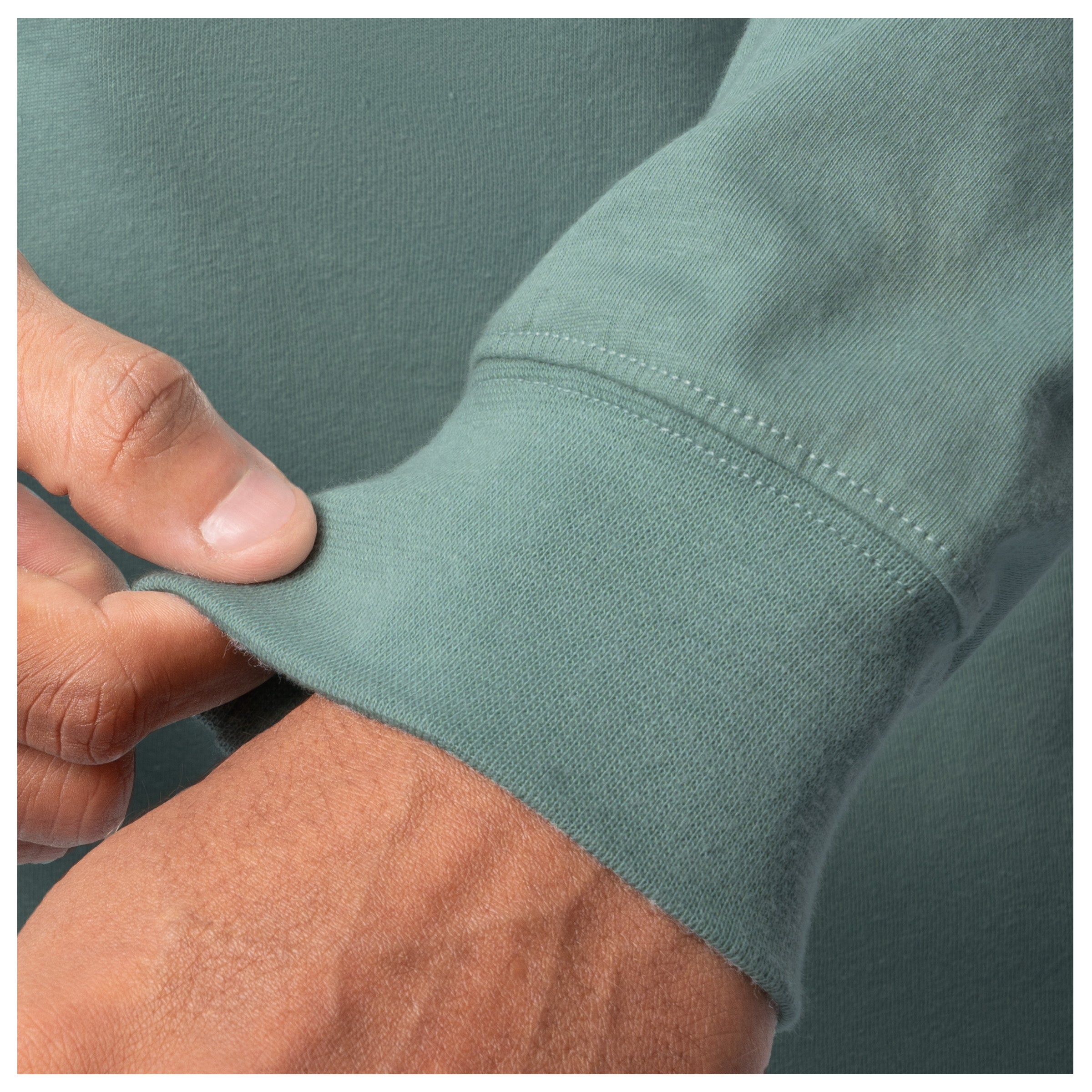 Close-up of a hand adjusting the cuff of a green shirt.
