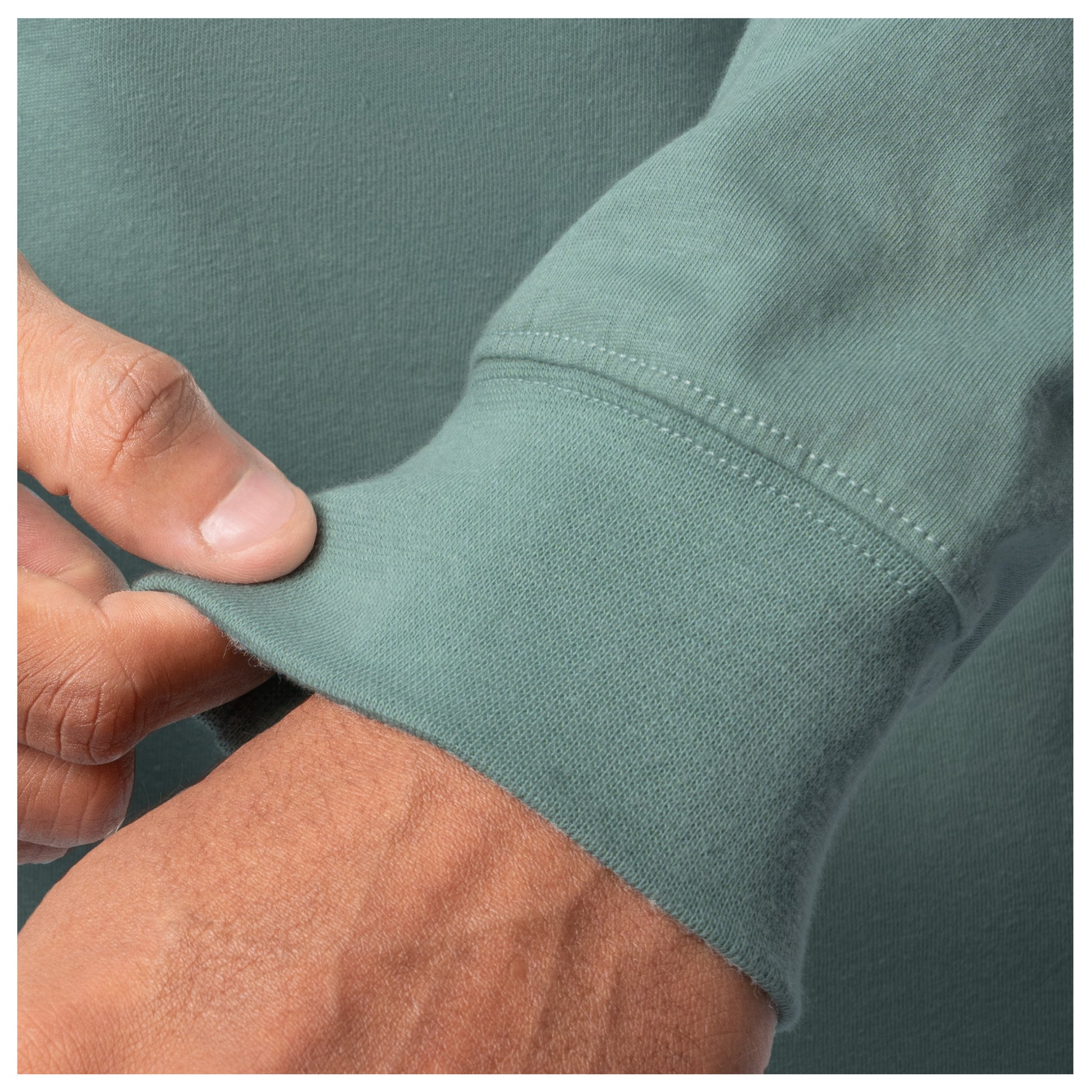 Close-up of a hand adjusting the cuff of a green shirt.