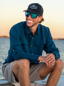 Man smiling wearing sunglasses and a blue button down