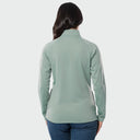 A woman viewed from the back wearing a blue surf long-sleeve quarter-zip pullover and blue jeans, set against a plain light gray studio background.