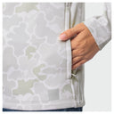 Close-up of a woman wearing a light gray and off-white camouflage zip-up jacket, showing a hand reaching into a side pocket.