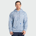 A man wearing a light blue mallard camo hoodie with a small blue logo patch on the pocket, standing against a light gray background.