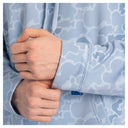 Close-up of a person wearing a light blue hoodie with a white abstract wavy pattern, adjusting the cuff of the sleeve.