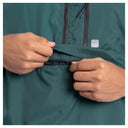 Close-up of a person's hands opening a zippered pocket on a dark teal green lightweight jacket.