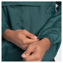 Close-up of a person's hands adjusting the elasticized cuff of a dark teal-green lightweight jacket.