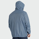 A man shown from the back wearing a hooded lightweight jacket in a muted dusty blue color, set against a plain light gray studio background.