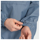 Close-up of a person's hands adjusting the elasticated cuff of a blue gingham-patterned jacket.