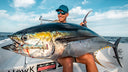 Ryan Morie holding a large tuna fish on a boat with a clear sky background