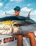 Man holding a large fish on a boat with a clear sky background