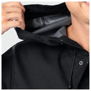 Close-up of a person wearing a black hooded jacket, pulling the hood open to show the gray inner lining. A hand is visible on the left and part of the person's face and neck are visible on the right.