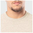 Close-up of a person wearing a beige sweater on a light gray background