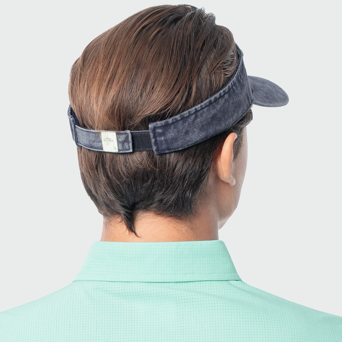 Person wearing a navy visor on a plain background