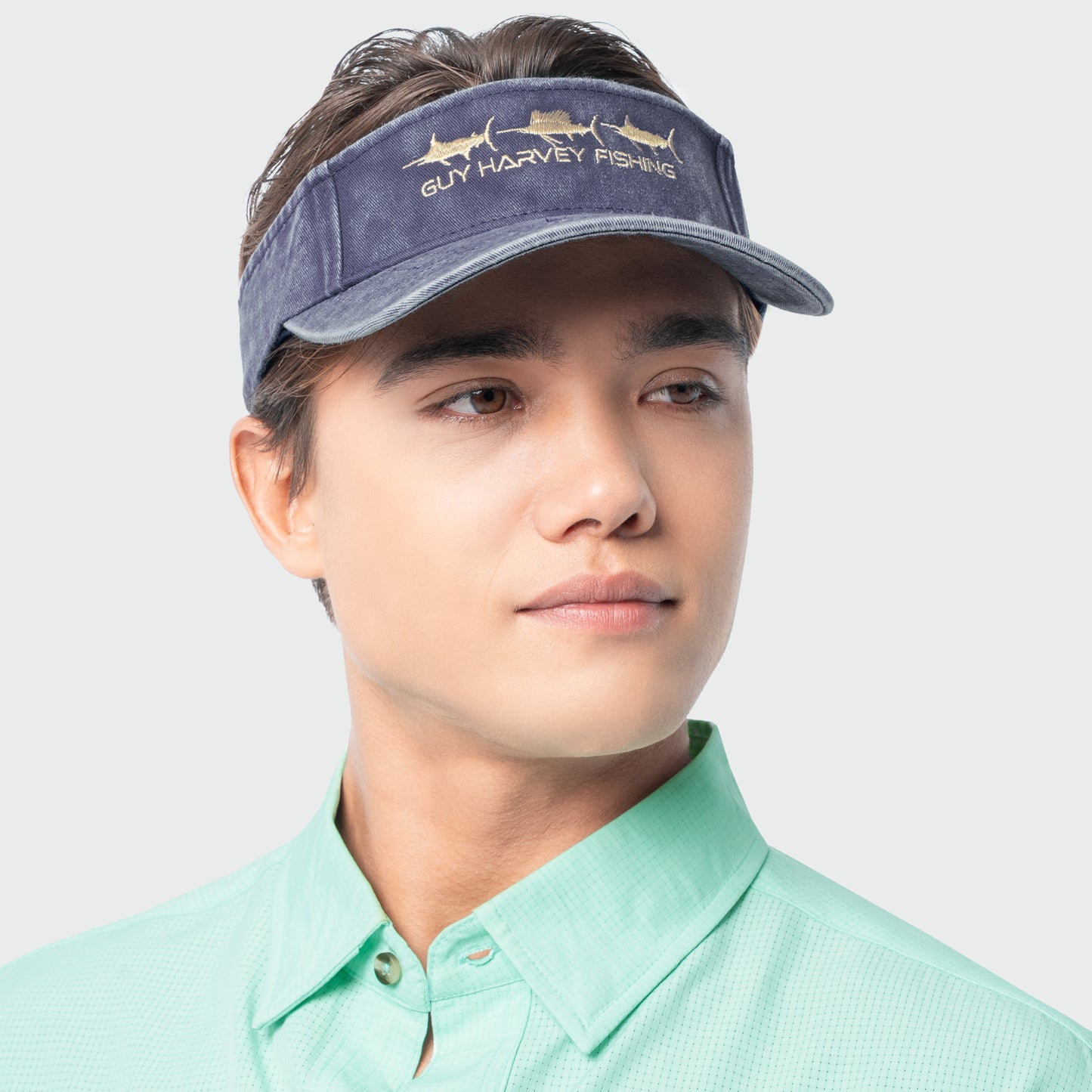 Person wearing a Navy Guy Harvey fishing visor on a plain background