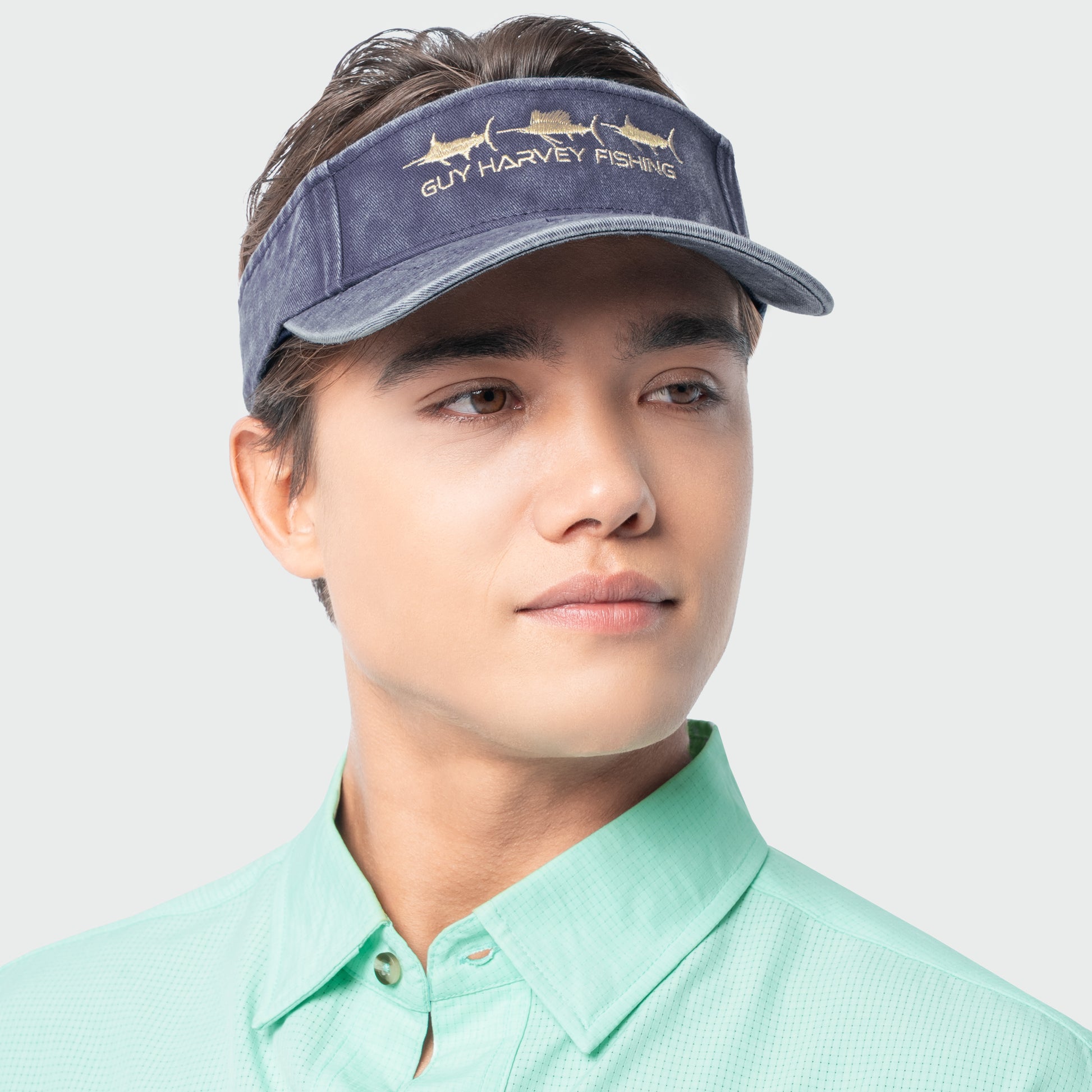 Person wearing a Navy Guy Harvey fishing visor on a plain background