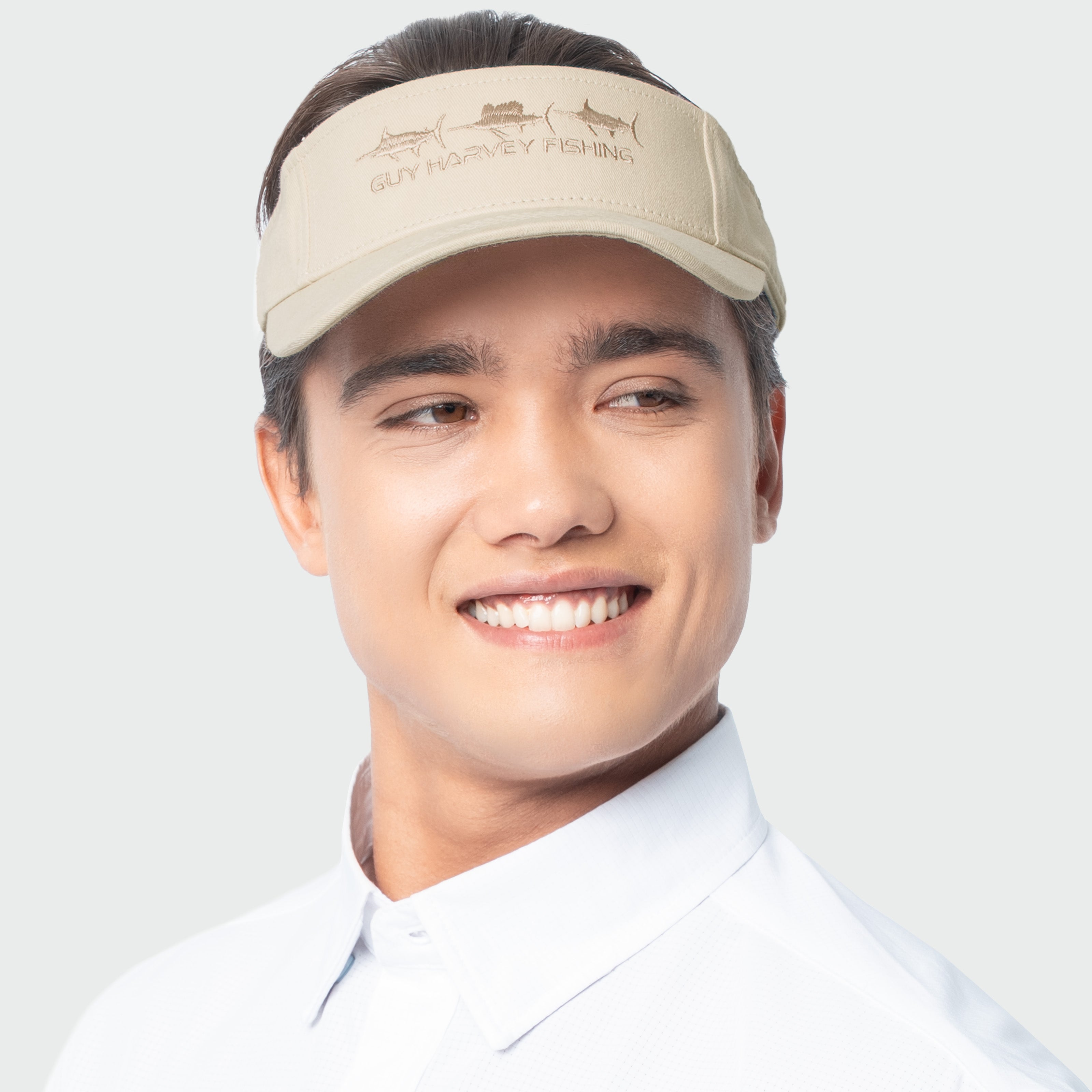 Man wearing a beige visor with a words Guy Harvey Fishing on a white background