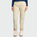 Beige fishing pants with an elastic waistband and side technical pocket, shown on a model from the waist down wearing a navy top and light-colored rain boots against a light gray background.