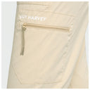 Close-up of a beige pair of fishing pants showing a zippered pocket with the brand name 'GUY HARVEY' printed in white on the pocket flap.