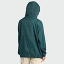 A person shown from the back wearing a dark teal hooded windbreaker jacket and light beige pants against a light gray studio background.