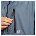 Close-up of a person's hand adjusting a black zipper on a slate blue grid-patterned jacket, with a small white brand tag visible near the bottom.