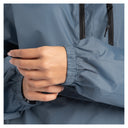 Close-up of a person wearing a slate blue lightweight jacket with elasticized cuffs and a black zipper, showing the hand adjusting the cuff.