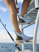 A woman in deck boots climbing a boat ladder