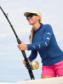 A woman fishing wearing a long sleeved tshirt with fish on the sleeves