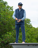 A man wearing Angler Edge fishing vest and pants from Guy Harvey while on a boat.