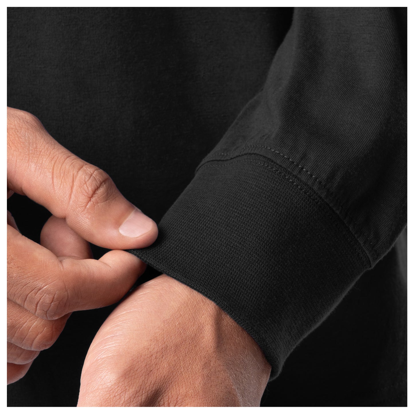 Close-up of a person adjusting the cuff of a black shirt.