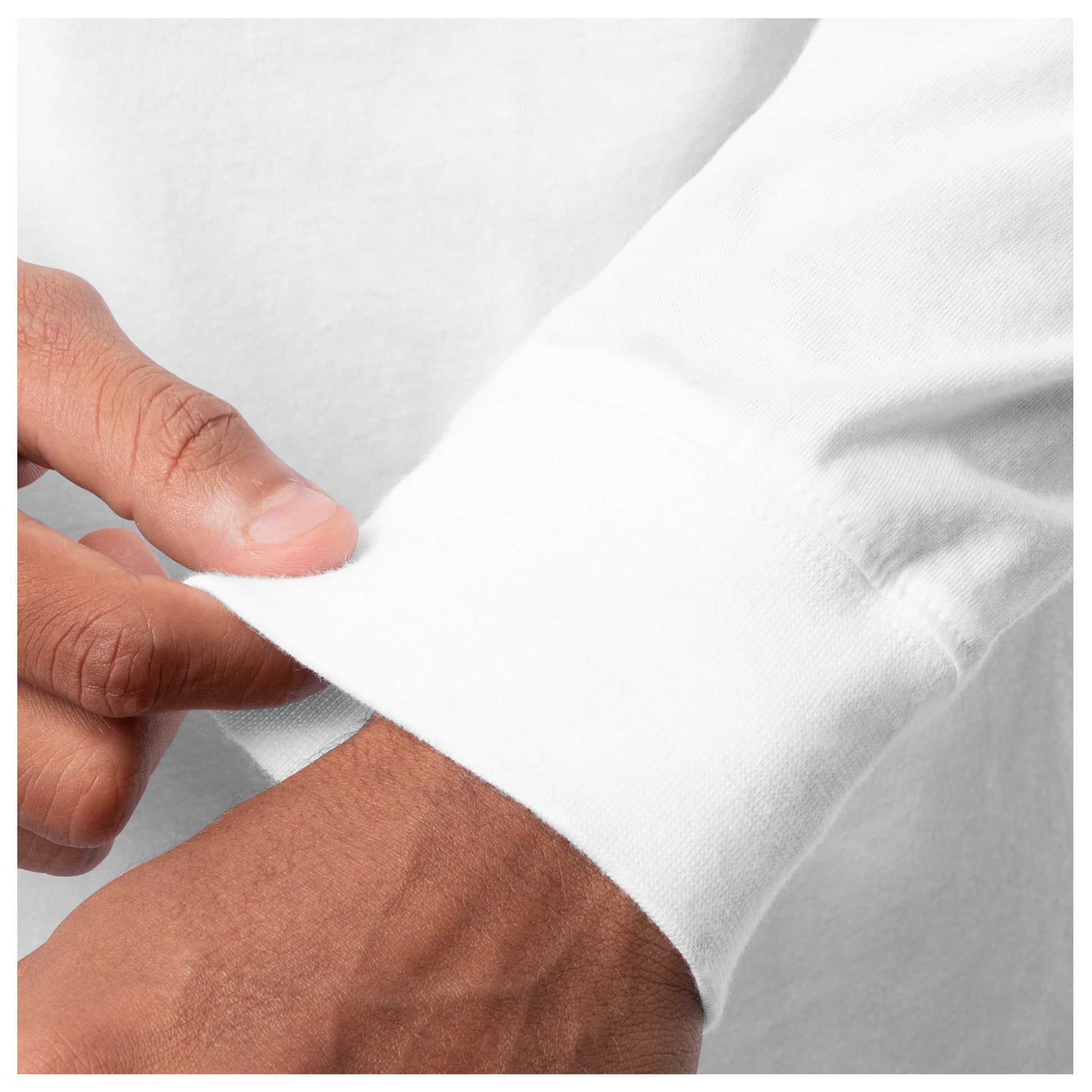 Close-up of a hand adjusting the cuff of a white shirt against a light gray background